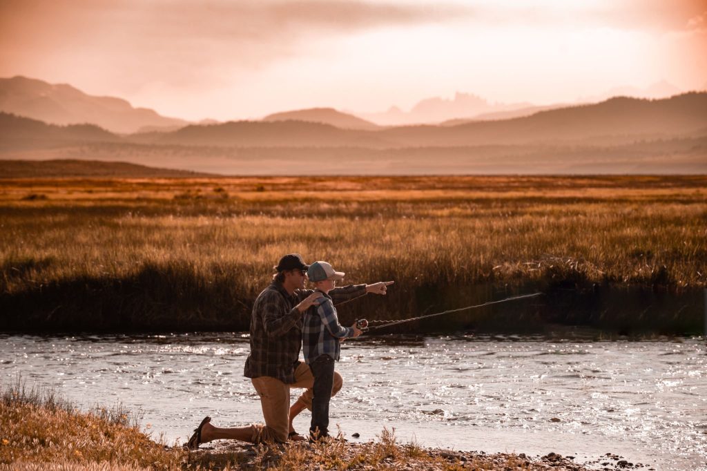 Father teaching son to fish in Sierra Mountains, California – symbolic of mentorship in outdoor storytelling